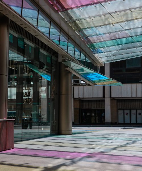 London, UK - 01 Jun 2020: Empty street scene during coronavirus lockdown on modern shopping walkway with coloured glass leaving patterns on pavement